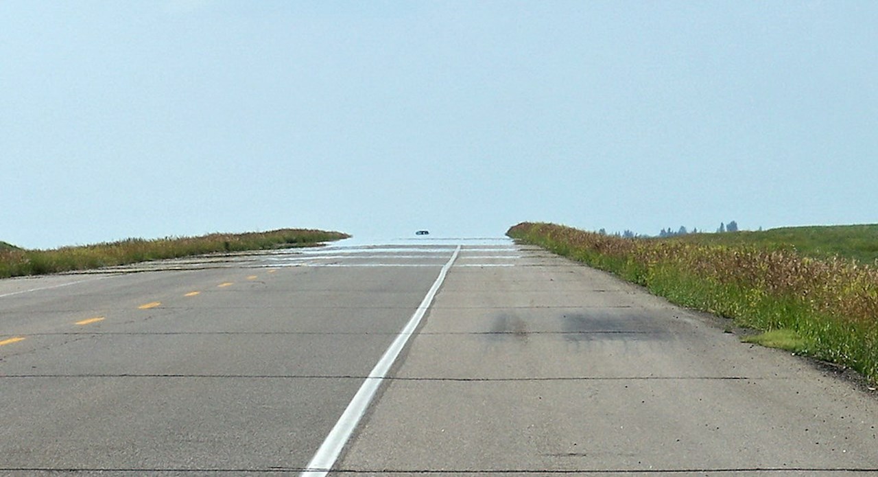 Why do we see an imaginary patch of water (mirage) on the road ahead?